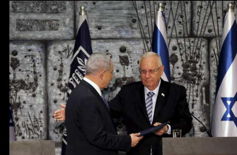 Prime Minister Benjamin Netanyahu receives a folder from President Reuven Rivlin during a ceremony in Jerusalem March 25 (photo credit: REUTERS)