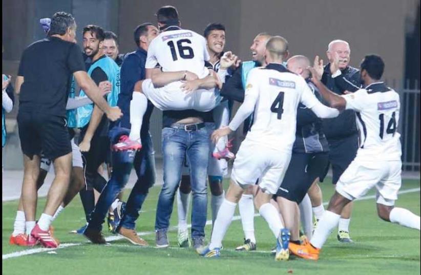 Hapoel Acre players and staff celebrated wildly after Elior Cider scored the team’s winner in Saturday night’s 1-0 victory over Hapoel Haifa (photo credit: ERAN LUF)