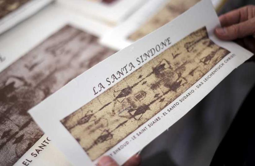 Souvenirs with the images of the Holy Shroud are seen in the bookstore next to the Cathedral of Turin during a media preview of the Exposition of the Holy Shroud (photo credit: REUTERS)