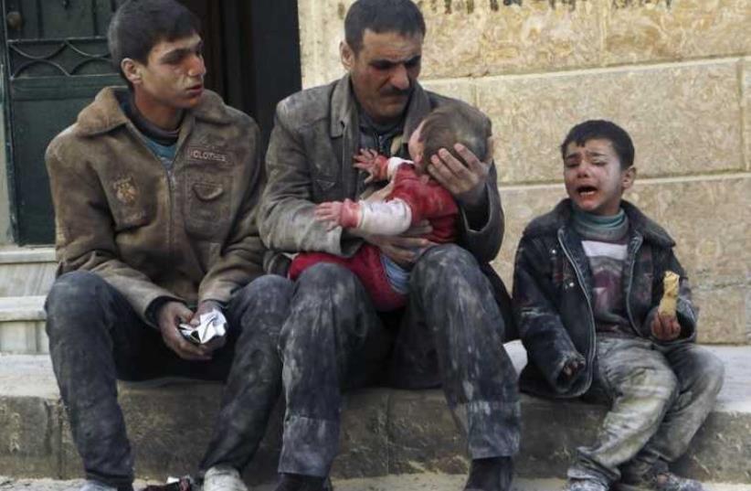 A man holds a baby saved from under rubble, who survived what activists say was an airstrike by forces loyal to Syrian President Bashar Assad in Aleppo (photo credit: REUTERS)