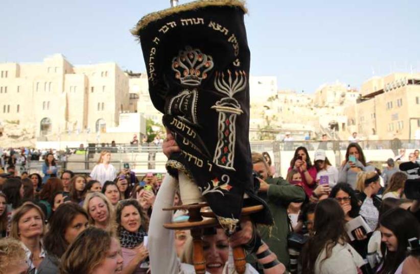Women of the Wall hoist a Torah scroll at the women's section of the Western Wall plaza. (photo credit: TOVAH LAZAROFF)