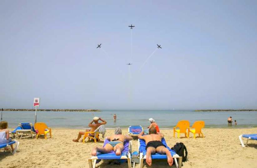 Beachgoers watch the Israeli Air Force Aerobatic team rehearse over the Mediterranean Sea in preparation for an aerial display on Israel's Independence Day in Tel Aviv April 20, 2015. (photo credit: REUTERS)