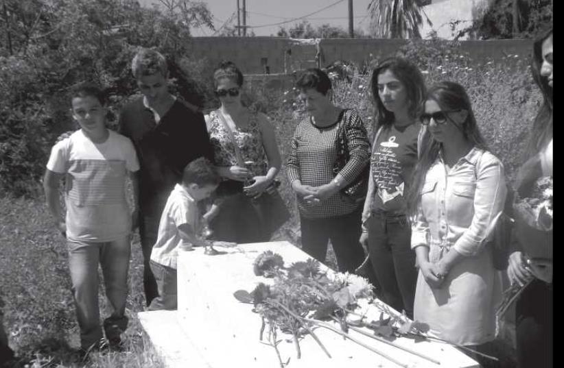 A young member of the Hindoyan family lays flowers at the Armenian Cemetery in Jaffa. (photo credit: Courtesy)