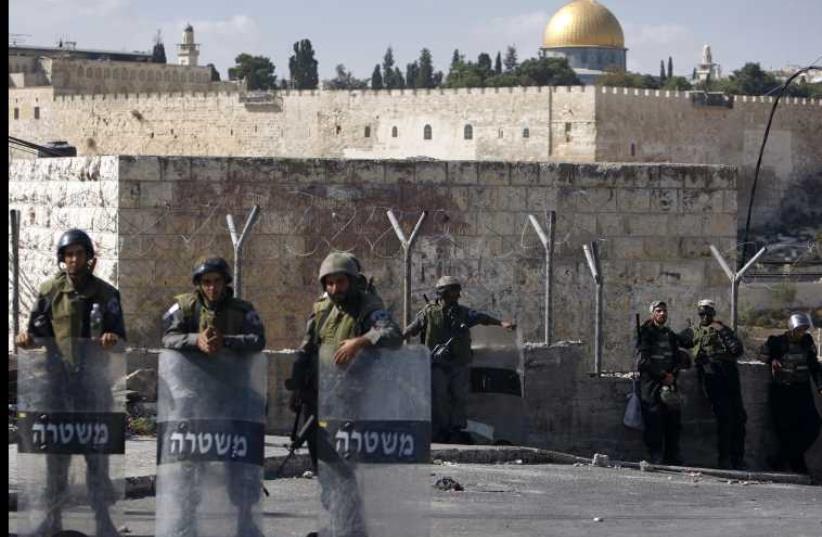 The Dome of the Rock is seen in the background as Israeli border police officers stand guard (photo credit: REUTERS)