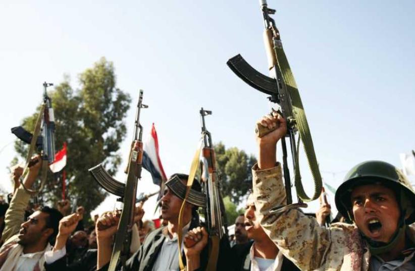 Houthi fighters raise their weapons as they demonstrate against an arms embargo imposed by the UN Security Council on the group, in Yemen’s capital of Sanaa last week. (photo credit: REUTERS)