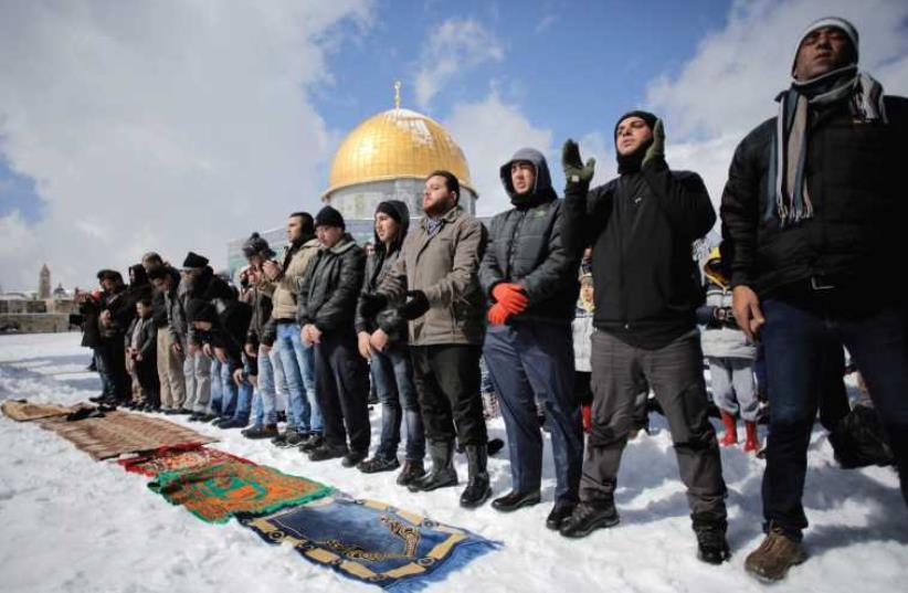 Palestinian men pray in front of the Dome of the Rock in February. (photo credit: REUTERS)