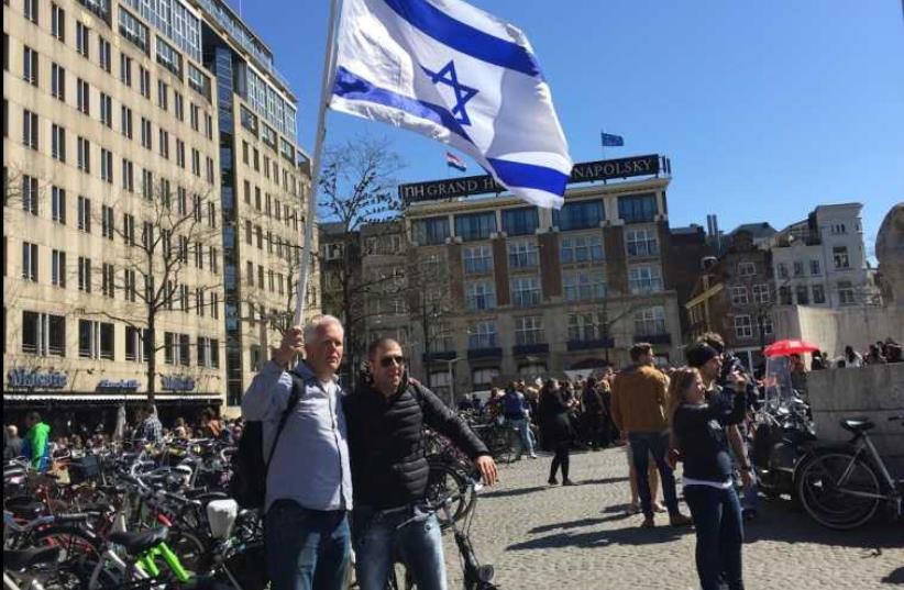 Pastor Stan Kamps waving the Israeli flag in Amsterdam as part of a campaign to fight anti-Semitism in Europe and show solidarity with European Jewry (photo credit: Courtesy)