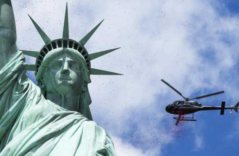 A helicopter flies above the Statue of Liberty in New York Harbor (photo credit: REUTERS)