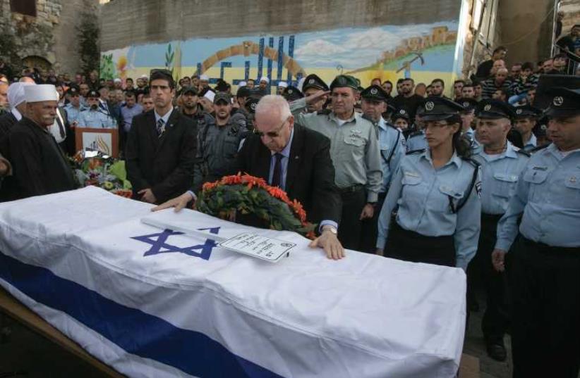 PRESIDENT REUVEN Rivlin touches the flag draped coffin of Israeli Druze police officer Zidan Nahad (photo credit: REUTERS)