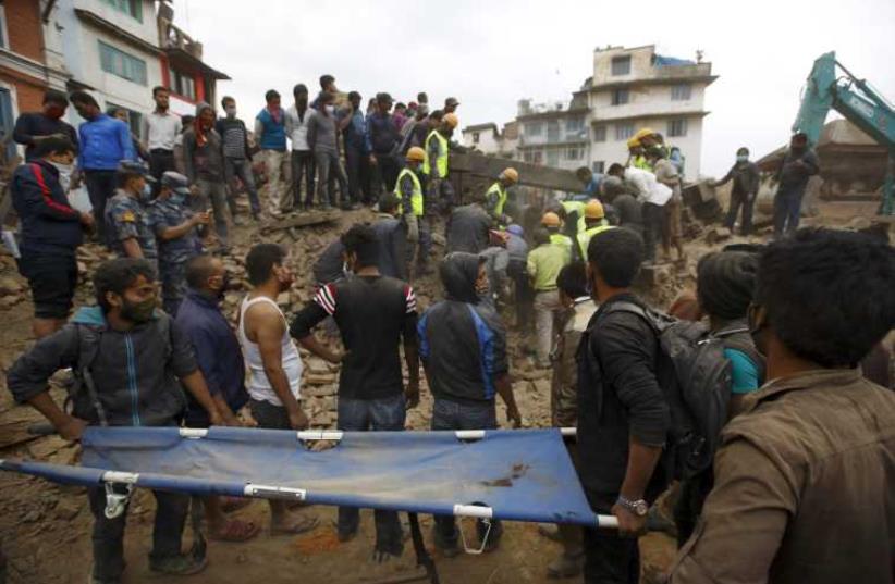 Rescue workers search for bodies as a stretcher is kept ready after an earthquake hit, in Kathmandu, Nepal April 25, 2015 (photo credit: REUTERS)