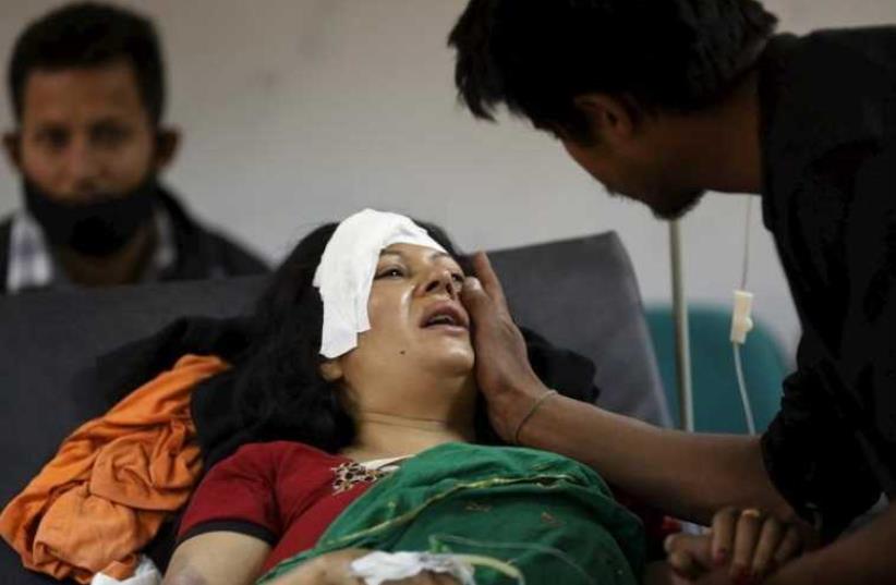 A boy comforts his mother who was injured during an earthquake, at a trauma center in Kathmandu (photo credit: REUTERS)