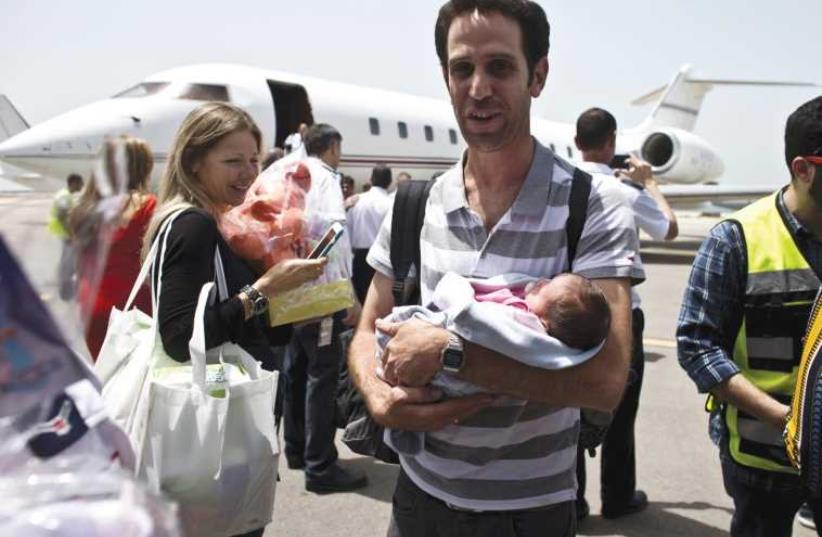 A man holds his baby, born to a surrogate mother, after being evacuated from Nepal and landing at Sde Dov Airport in Tel Aviv (photo credit: NIR ELIAS / REUTERS)