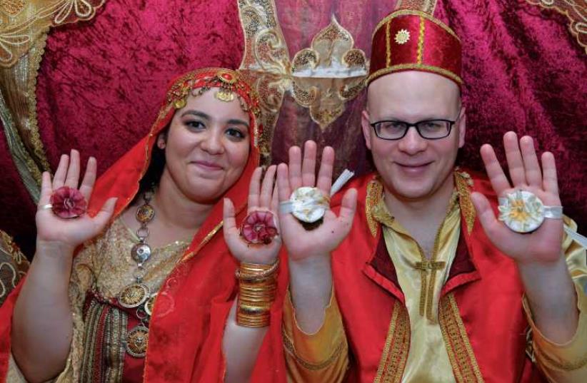 The writer’s son and daughter-in-law hold up their hennaed hands for a photo-op. (photo credit: YEHUDIT HELFON)