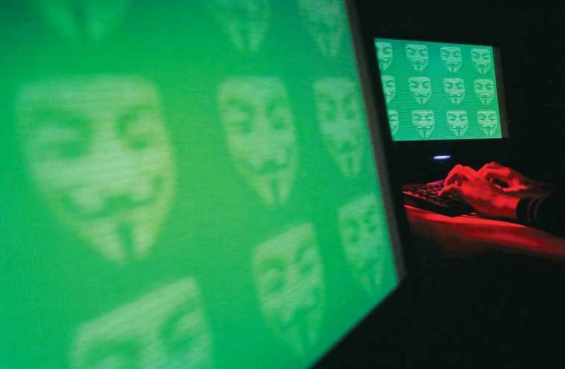 The logo for the cyber hacking group ‘Anonymous’ is seen on computer screens. (photo credit: REUTERS)