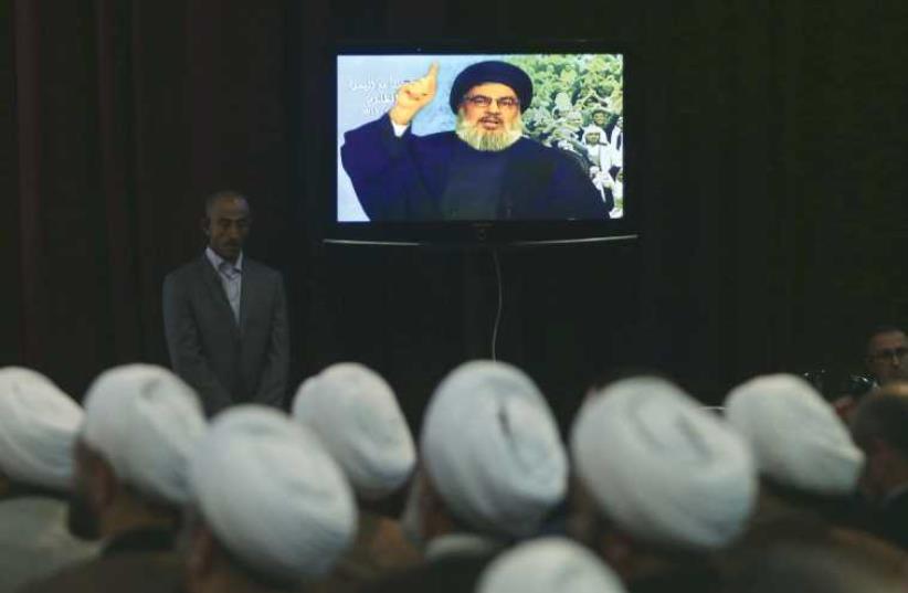 Hassan Nasrallah talks to his Lebanese and Yemeni supporters via a giant screen during a speech against US-Saudi aggression in Yemen, in Beirut’s southern suburbs on April 17. (photo credit: REUTERS)