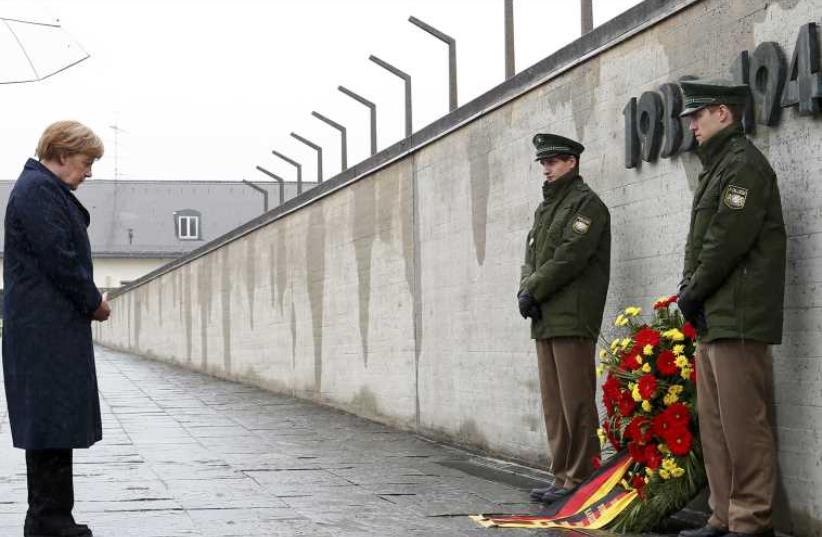 German Chancellor Merkel observes a moment of silence as she lays a wreath during a ceremony at the memorial in the former German Nazi concentration camp in Dachau. (photo credit: REUTERS)