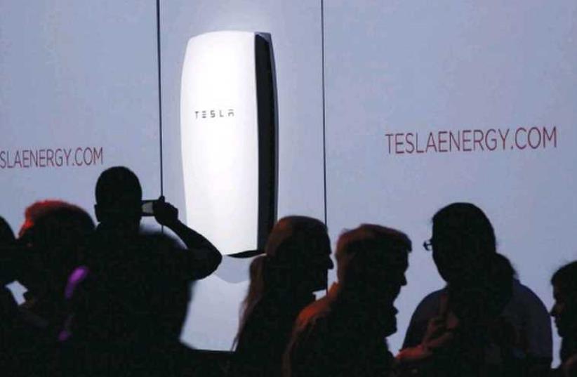 ATTENDEES TAKE pictures of the new Tesla Energy Powerwall Home Battery during an event at Tesla Motors in Hawthorne, California, last Thursday. (photo credit: REUTERS)