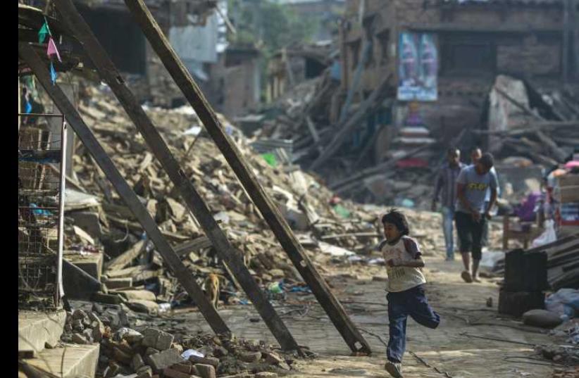An earthquake survivor runs past collapsed houses on the outskirts of Kathmandu, May 5. (photo credit: REUTERS/ATHIT PERAWONGMETHA)