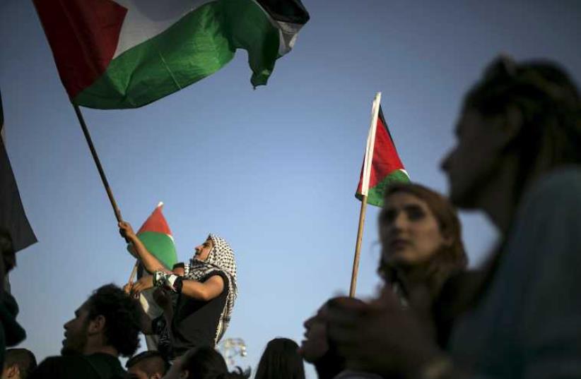 Israeli Arab protesters in Rabin Square in Tel Aviv wave Palestinian flags (photo credit: REUTERS)