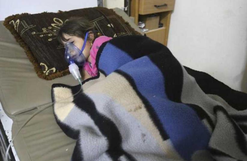 A girl, affected by what activists say was a gas attack, receives treatment inside a makeshift hospital in Kfar Zeita village in the central province of Hama (photo credit: REUTERS)