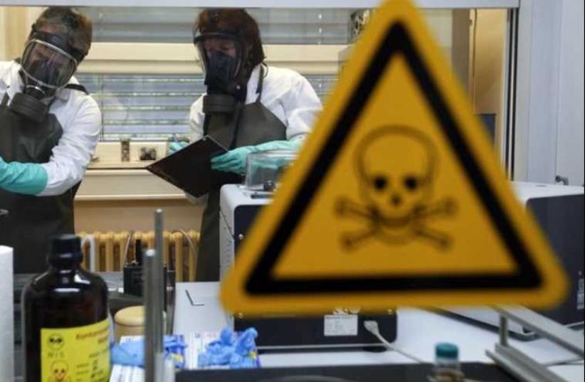 Employees of the Research Institute for Protective Technologies, Nuclear, Biological and Chemical Protection (WIS) inspect a dummy sample which is contaminated with a substance similar to the chemical weapon Sarin. (photo credit: REUTERS)