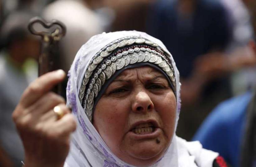 A woman holds a symbolic key as she takes part in a rally ahead of "Nakba Day" in Ramallah on May 13, 2015 (photo credit: REUTERS)