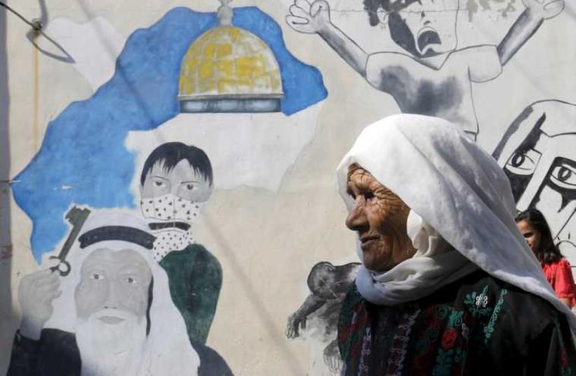 A Palestinian woman walks at Al-Baqaa Palestinian refugee camp near Amman (photo credit: REUTERS)