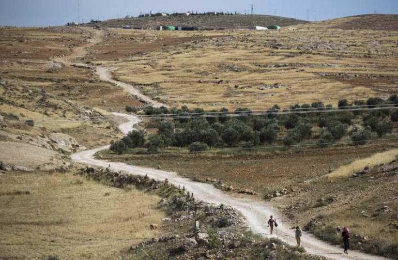 Palestinians walk on a dirt road near the West Bank Jewish settlement of Maon, south of Hebron May 19, 2014 (photo credit: REUTERS)