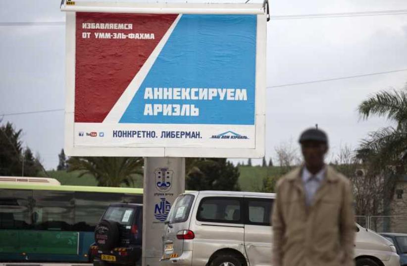 A man walks in front of a Yisrael Beytenu party campaign billboard in the southern city of Ashkelon (photo credit: REUTERS)