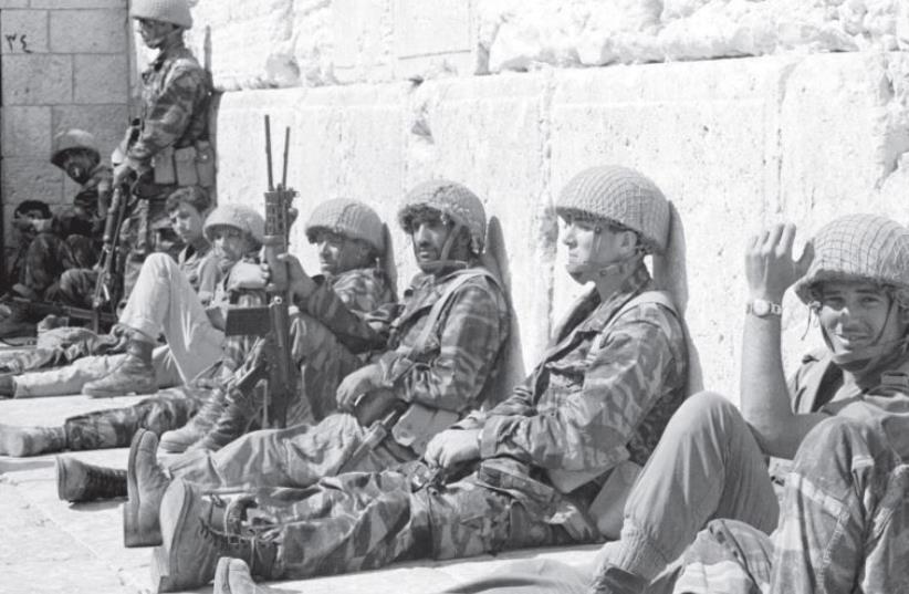 IDF soldiers sit in front of the Western Wall in June 1967 after it was captured during the Six Day War. (photo credit: REUTERS/IDF HANDOUT)