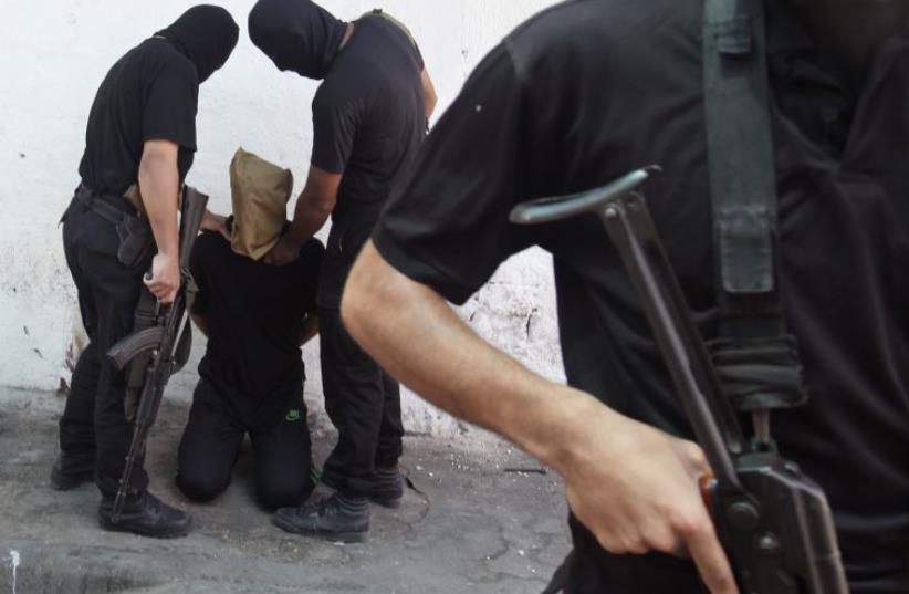 Hamas militants grab a Palestinian suspected of collaborating with Israel before being executed in Gaza City (photo credit: REUTERS)
