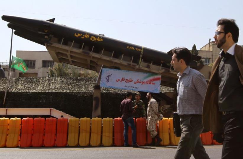 Iranian men walk past a long-range "Khalij Fars" anti-ship ballistic missile, displayed at a square in southern Tehran (photo credit: AFP PHOTO)