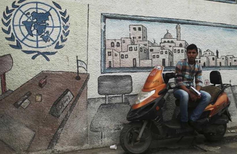 A Palestinian student sits on a motorcycle as he watches a protest at the gate of the headquarters of UNRWA in Gaza City (photo credit: REUTERS)
