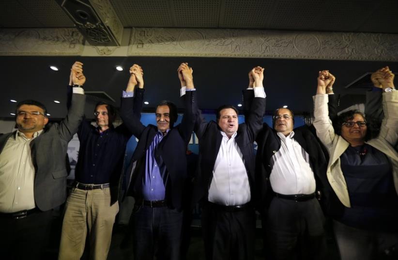 Ayman Odeh (3rd R), head of the Joint Arab List, reacts with members of the party after exit poll results in Nazareth March 17 (photo credit: REUTERS)