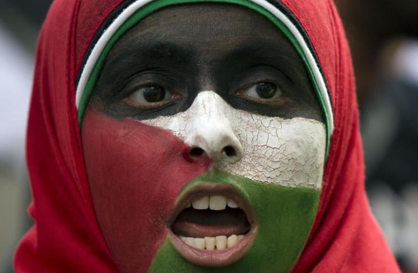 A protester with her face painted in the colors of the Palestinian flag chants during a pro-Gaza demonstration outside the Israeli embassy in London (photo credit: REUTERS)