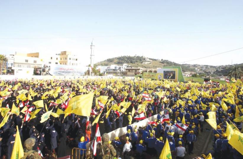 Residents gather to watch Hezbollah leader Sayyed Hassan Nasrallah on a screen during a televised speech at a festival celebrating Resistance and Liberation Day, in Nabatiyeh on May 24, 2015. (photo credit: REUTERS/ALI HASHISHO)