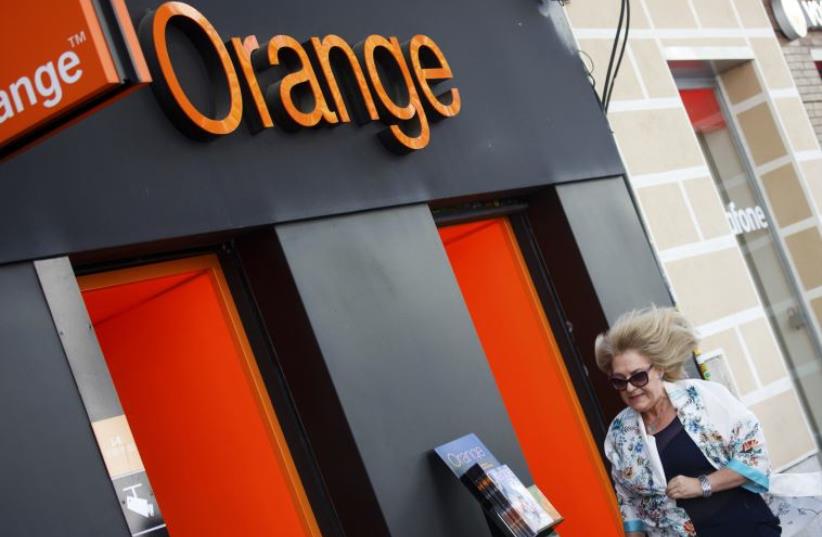 A woman walks past an Orange shop (photo credit: REUTERS)