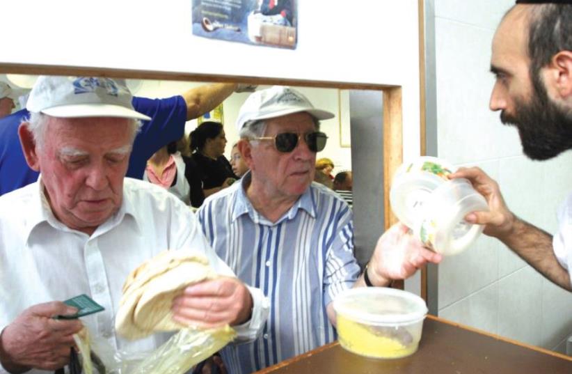A volunteer distributes food at a soup kitchen. (photo credit: ILLUSTRATIVE: MARC ISRAEL SELLEM)