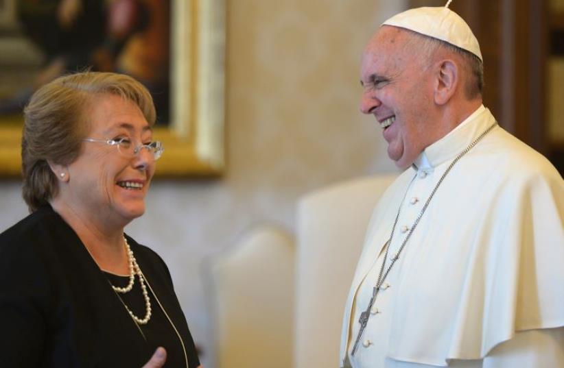 Pope Francis and Chile's President Michelle Bachelet laugh during a private audience at the Vatican (photo credit: AFP PHOTO POOL / ALBERTO PIZZOLI)