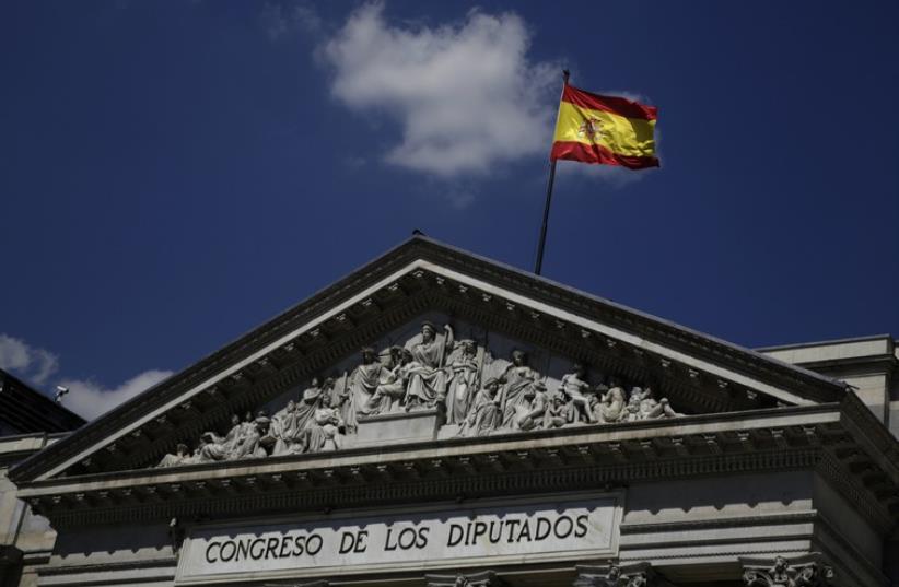 A Spanish flag waves over the Spanish parliament in Madrid (photo credit: REUTERS)