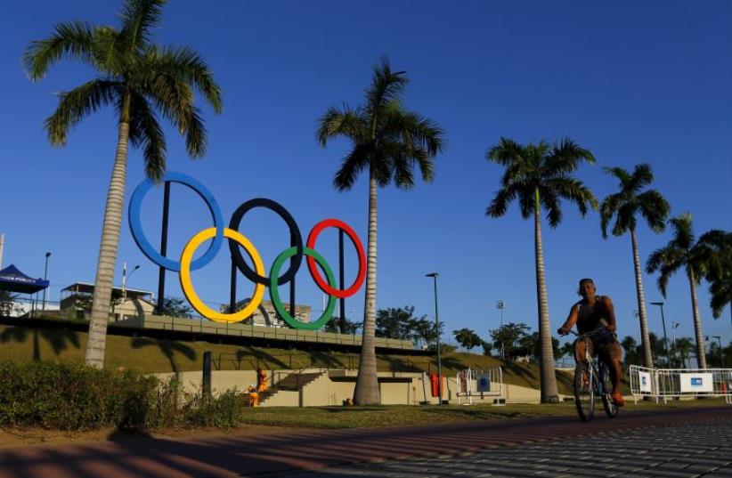 A man exercises next to the Olympic rings placed at the Madureira Park ahead the Rio 2016 Olympic Games (photo credit: REUTERS)