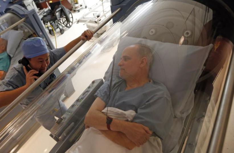 Doctor Andy Chiou (L) speaks to patient Carl Dolson in a hyperbaric chamber in Peoria, Illinois (photo credit: REUTERS)