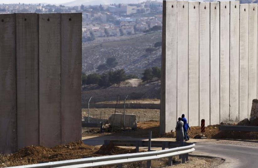 Palestinians walk near an opening in Israel's security fence in the east Jerusalem neighborhood of A-tur (photo credit: REUTERS)