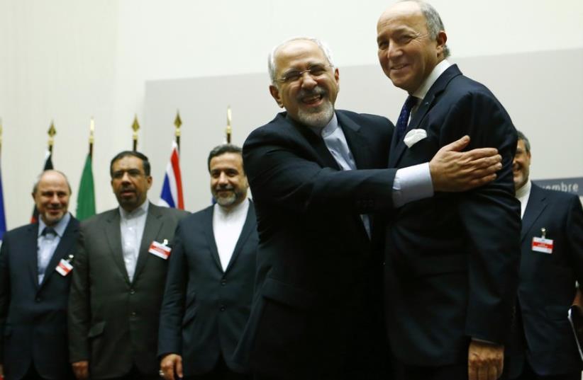 Iranian Foreign Minister Mohammad Javad Zarif hugs French Foreign Minister Laurent Fabius after a ceremony at the United Nations in Geneva November 24, 2013 (photo credit: REUTERS)