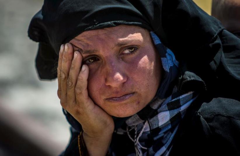 A woman reacts as she rests from walking back to Tel Abyad town, Raqqa governorate, after fleeing Maskana town in the Aleppo countryside (photo credit: REUTERS)