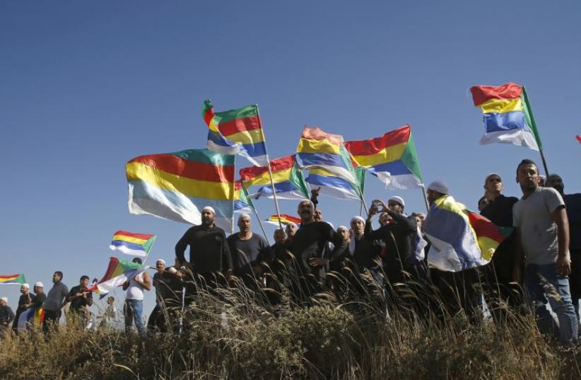 Members of the Druse community watch the fighting in the Druse village of Khadr in Syria as they stand on the Israeli side of the border fence between Syria and the Golan Heights (photo credit: REUTERS)
