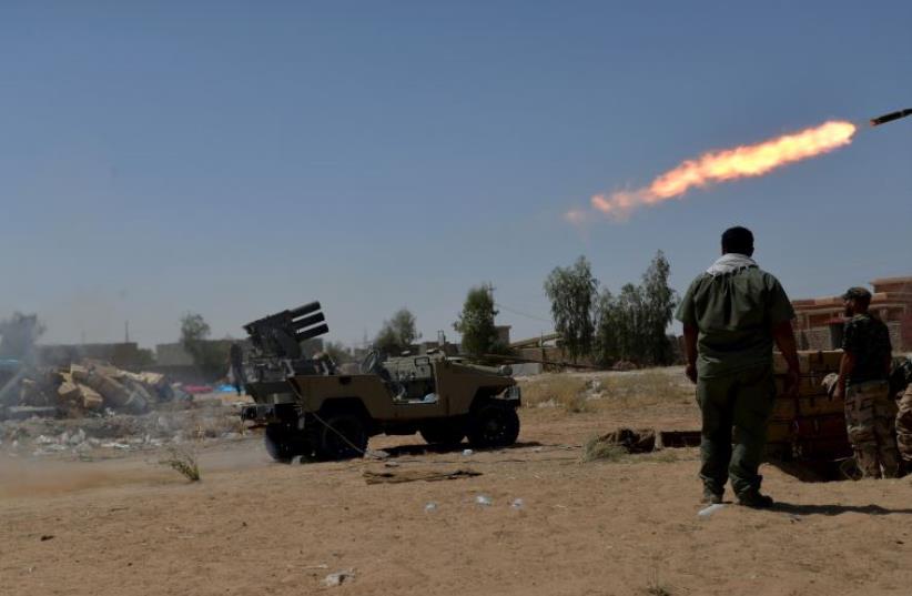 Shiite fighters launch a rocket towards Islamic State militants on the outskirt of Bayji (photo credit: REUTERS)