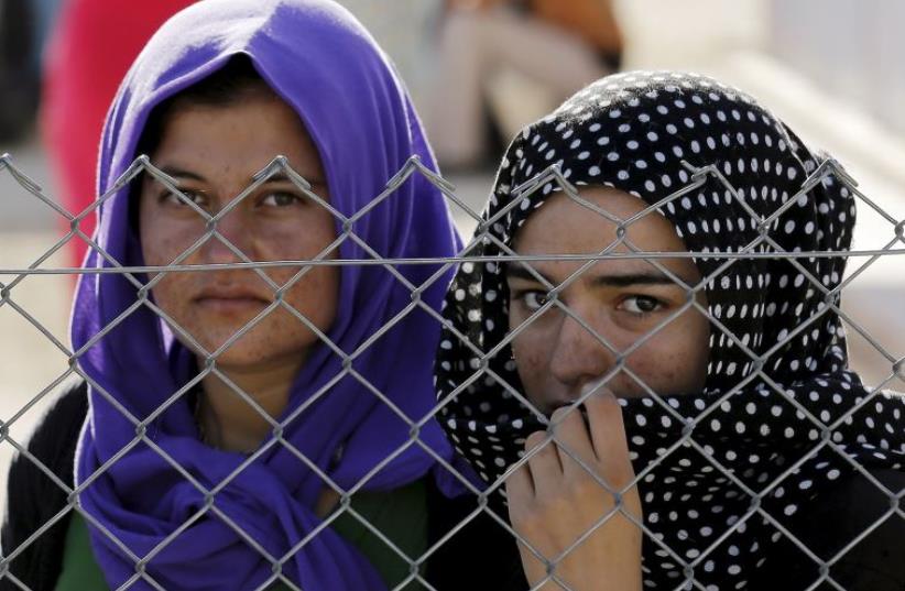 Yazidi refugees stand behind fences in the southern Turkish town of Midyat (photo credit: REUTERS)