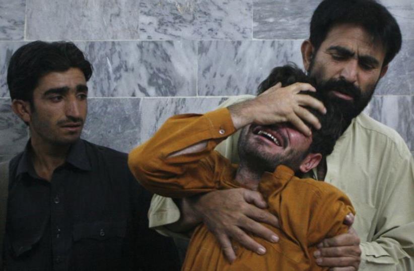 A man is comforted by his relative after he arrived at the local hospital in Quetta (photo credit: REUTERS)