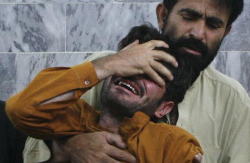 A man is comforted by his relative after he arrived at the local hospital in Quetta (photo credit: REUTERS)